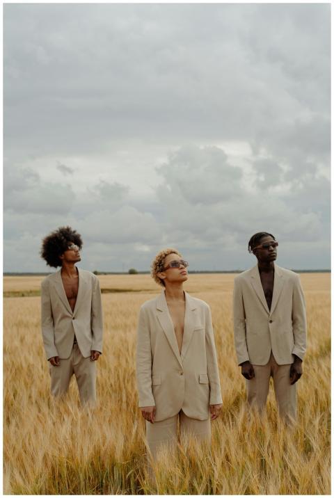 Three fashionable models wearing beige suits stand