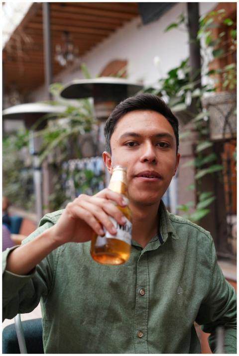 Young man in green shirt holding a beer bottle at