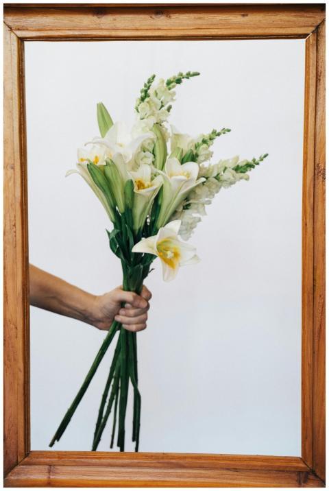 A hand holding a bouquet of white lilies elegantly