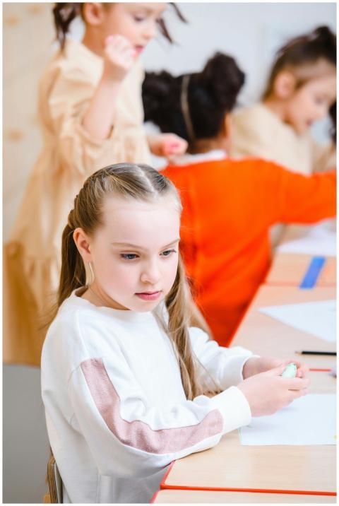 Kids working on crafts in a bright classroom setti