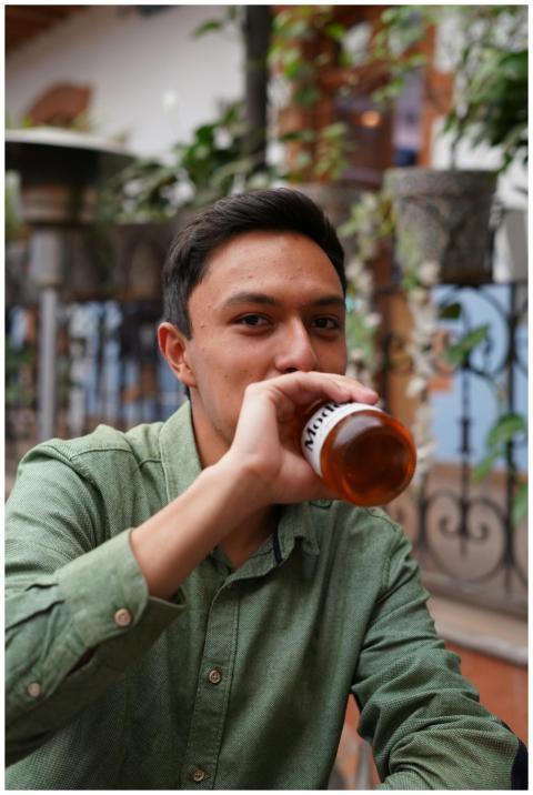 Young man in green shirt enjoying a beer outdoors