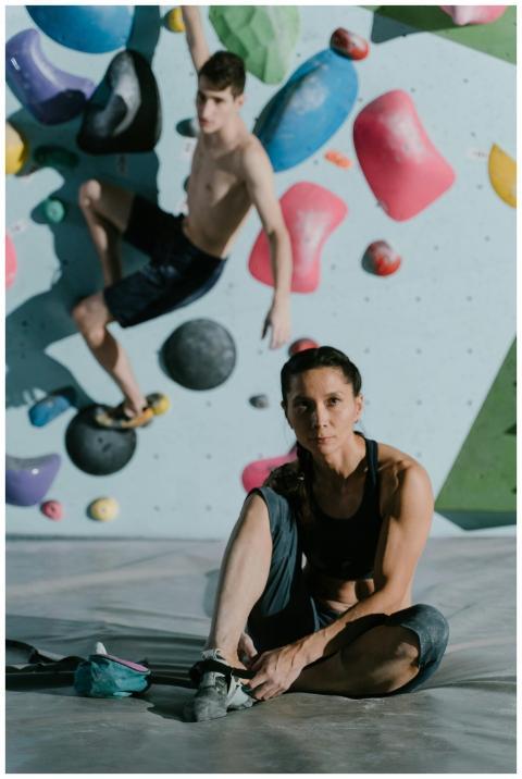 Two adults engaged in indoor bouldering, emphasizi