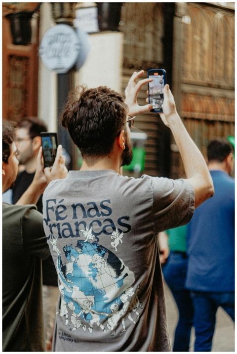 Man capturing street scene on phone in busy urban