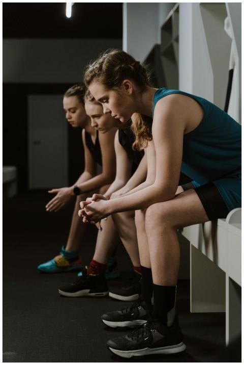 Three women in activewear sitting pensively in a l