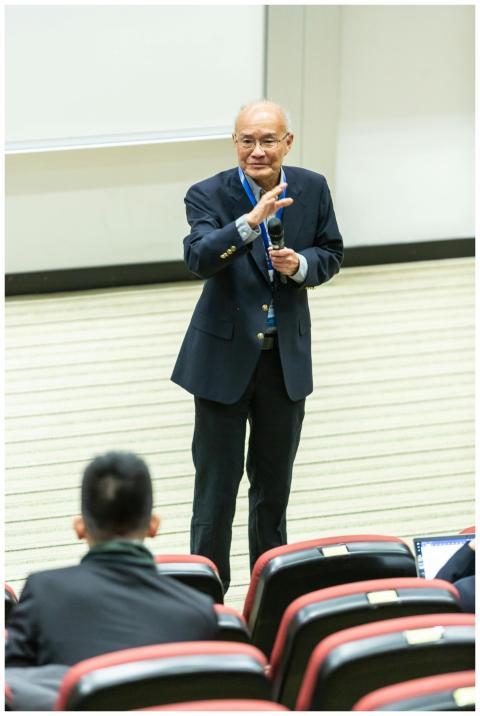 Elderly man delivering a speech in a lecture hall,
