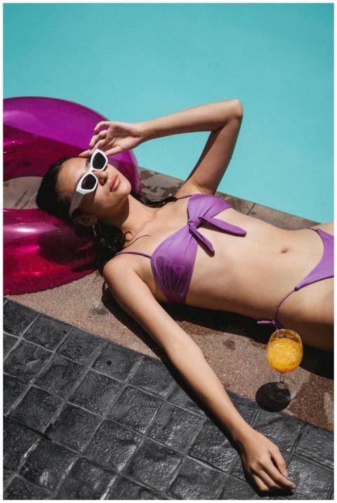 A young woman in a purple bikini enjoys sunbathing