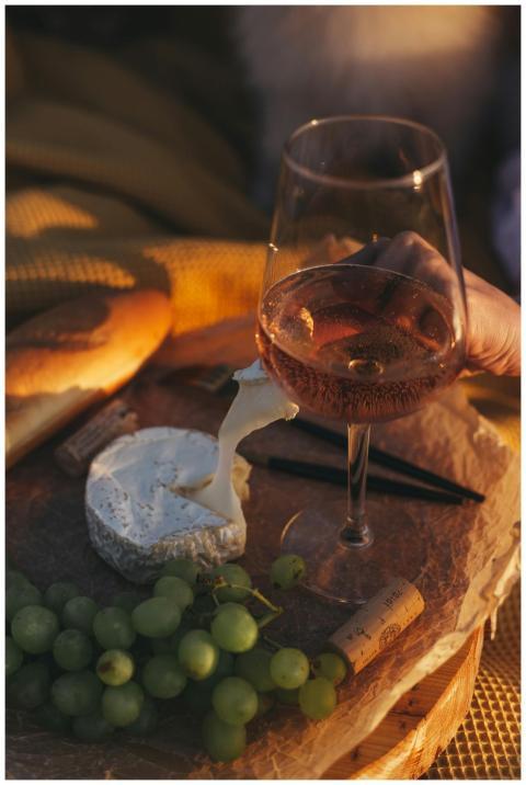 A serene outdoor picnic setup with wine, cheese, g