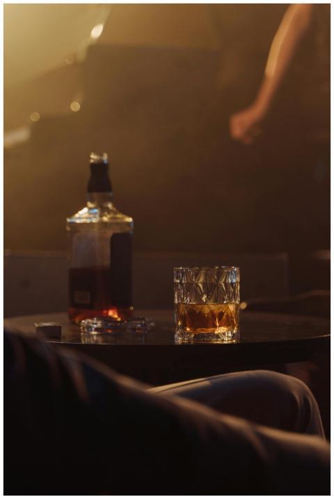 Moody bar setting featuring a whiskey bottle and g