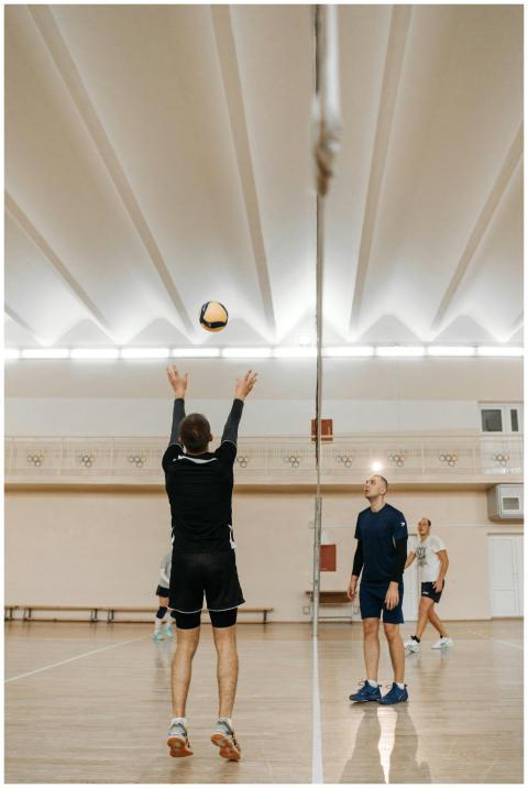 Group of men playing volleyball indoors during pra