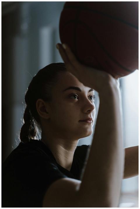 Teen girl focusing on making a basketball shot ind