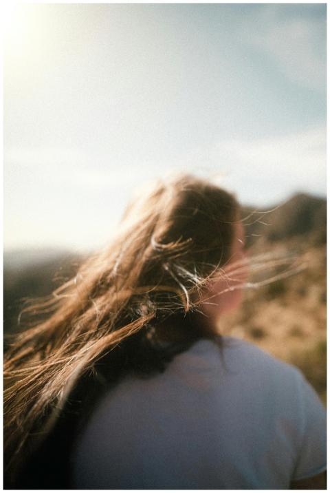 A woman with flowing hair enjoys a windy sunset at