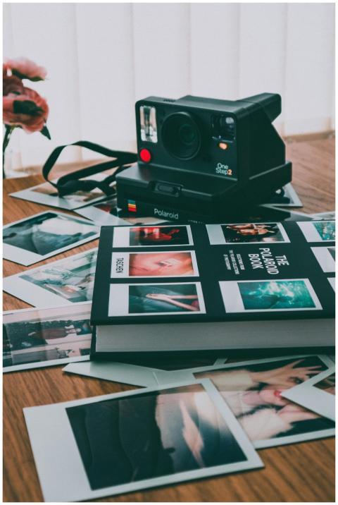 A vintage Polaroid camera with scattered instant p