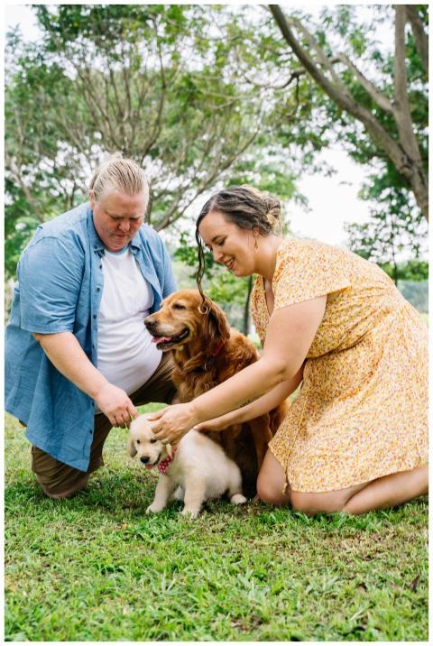 A loving couple plays with their two dogs in a sun