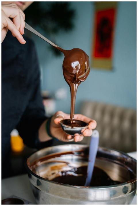 Close-up of chocolate ganache pouring into a conta