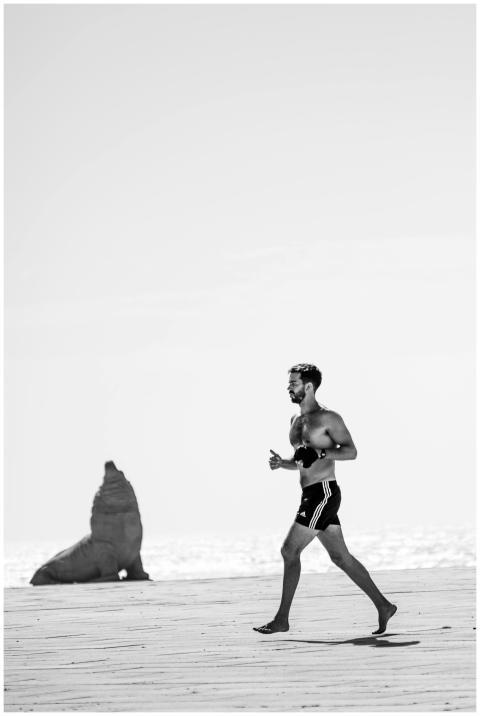 Black and white photo of a man jogging by the sea