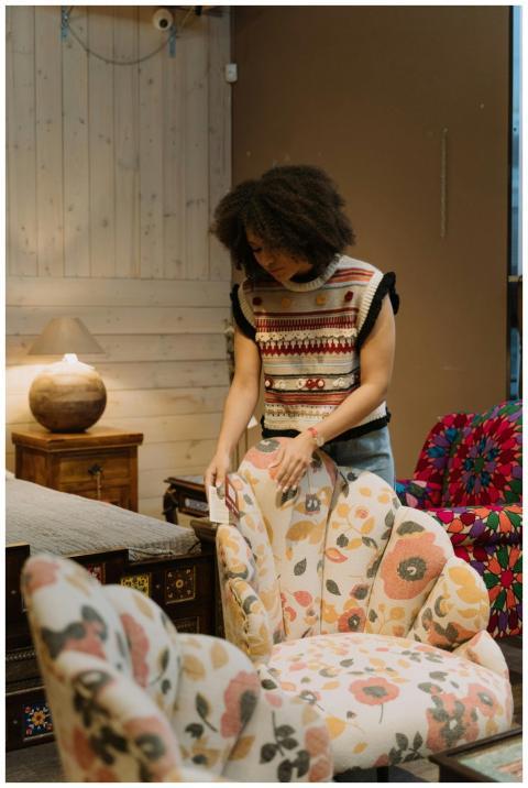 Woman in cozy store setting arranging floral armch