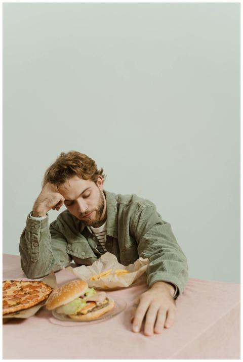 Young man appears tired with fast food burger and