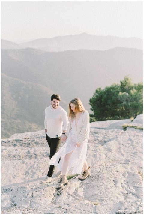 A happy couple walks hand in hand on a mountain tr