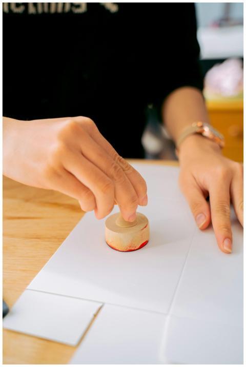 Close-up of a person using a wooden stamp on white