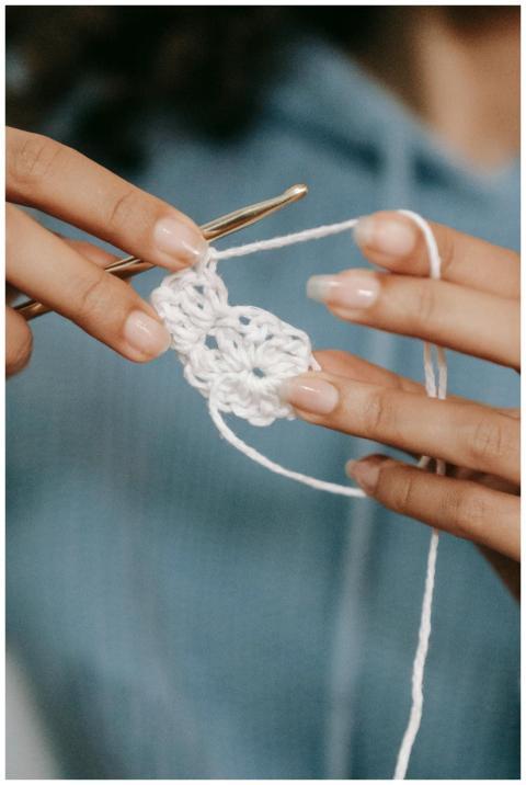 Crop anonymous female artisan with hook and white