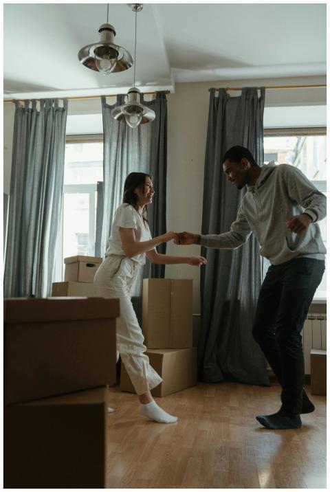 Happy couple dancing among cardboard boxes in thei