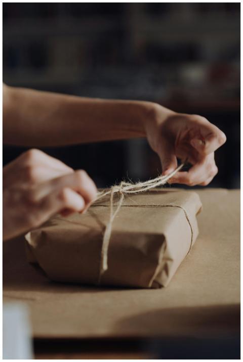 Hands tying twine around a craft paper wrapped gif