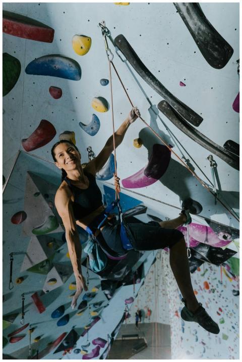 A woman engaged in indoor rock climbing, showcasin