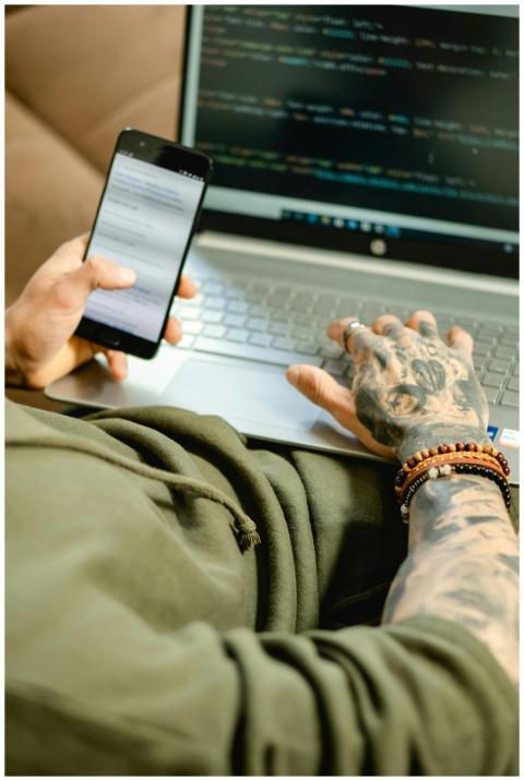 A focused individual coding on a laptop while chec
