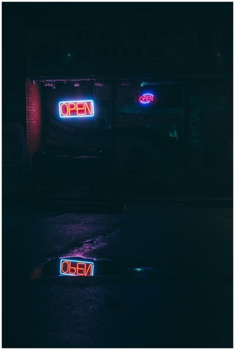 A dark urban storefront at night with neon 'Open'