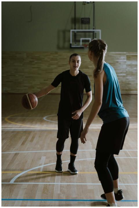 Two women engaging in a basketball game on an indo