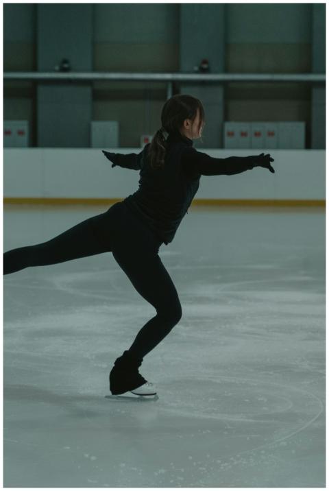 A woman in black performs a figure skating routine
