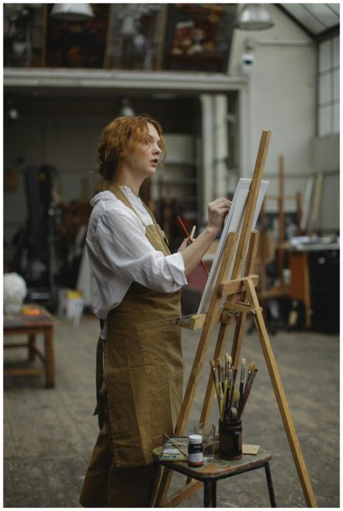 A focused female artist paints on canvas in an art