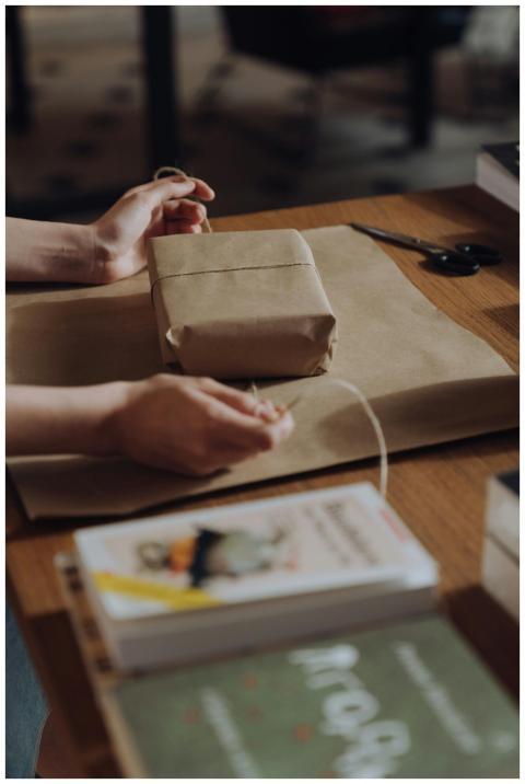 Hands skillfully wrapping a book with brown craft