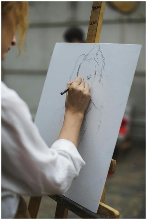 A focused artist sketching a portrait on canvas wi