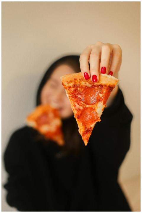 A woman with red nails holding a pepperoni pizza s