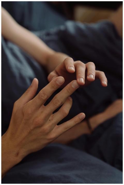 Close-up of hands touching on blue bedding, convey