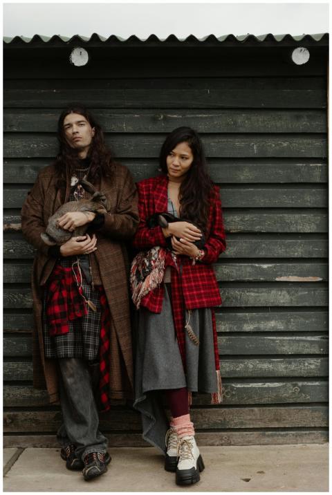 A fashionable couple holds rabbits against a rusti