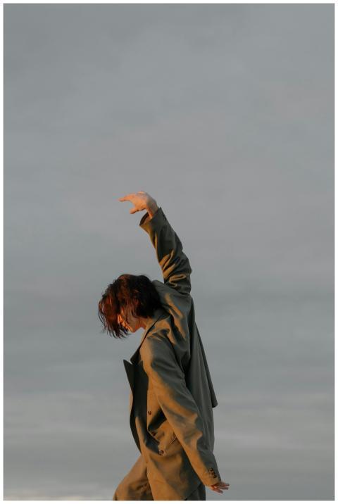 A dancer in a suit gracefully poses outdoors again
