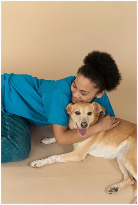 Woman happily embracing her pet dog in a studio, s