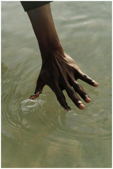 A close-up of a hand gently touching water, captur