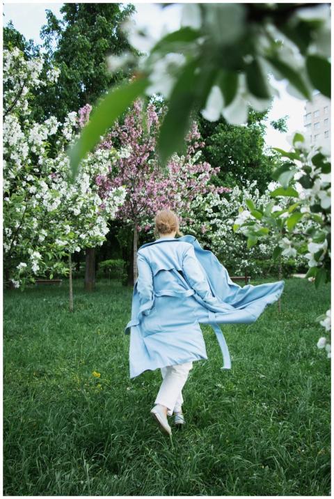 A woman in a blue coat walks through a lush garden