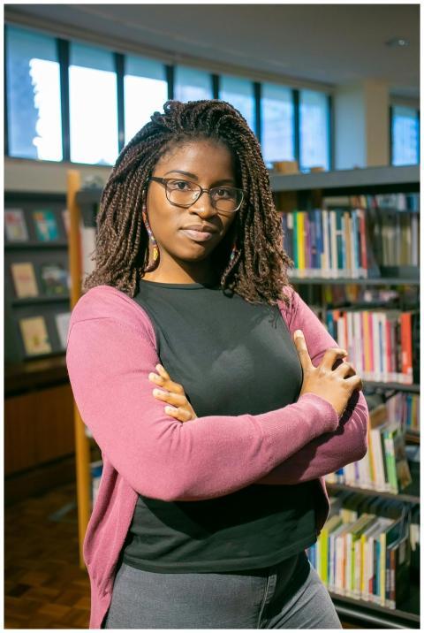 Young woman with glasses stands confidently with a