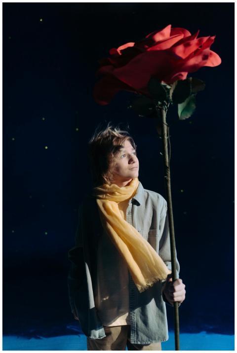 A child dressed as the Little Prince holds a giant