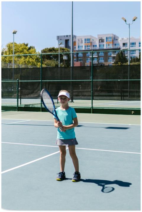 A young girl enjoying a game of tennis on an outdo