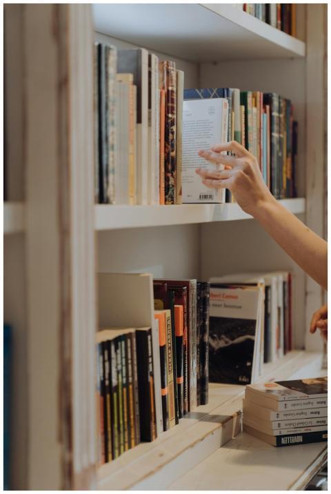 A person organizing books on a library bookshelf,