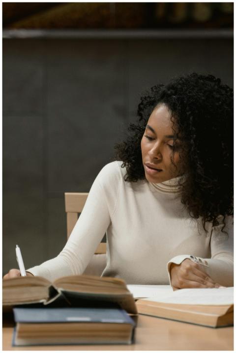 A focused woman writing and studying inside a mode