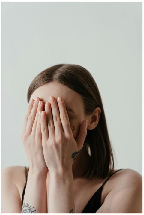 A woman covers her face with hands, exuding a sens