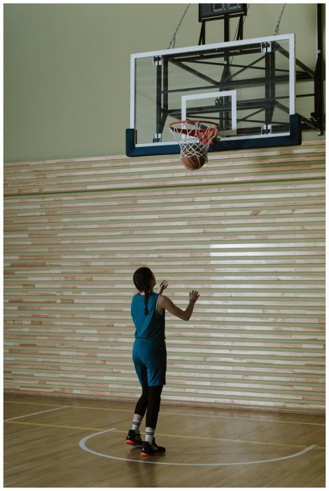 A teenager practicing basketball indoors, focusing