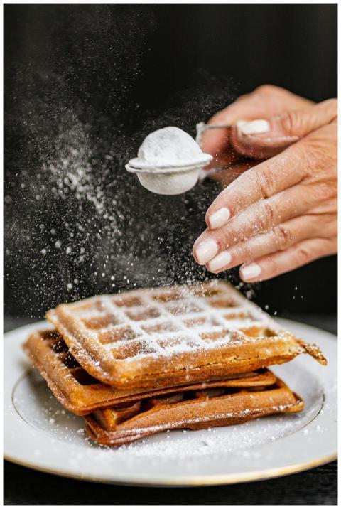 Close-up of waffles being dusted with powdered sug