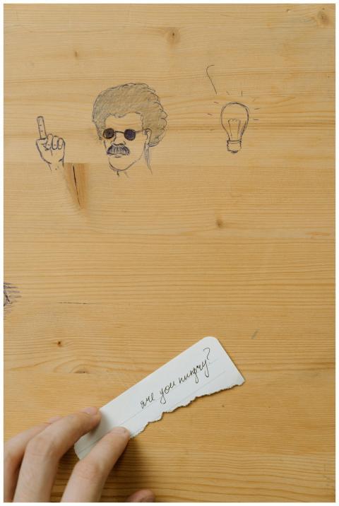 Close-up of doodles on a wooden desk with a hand h